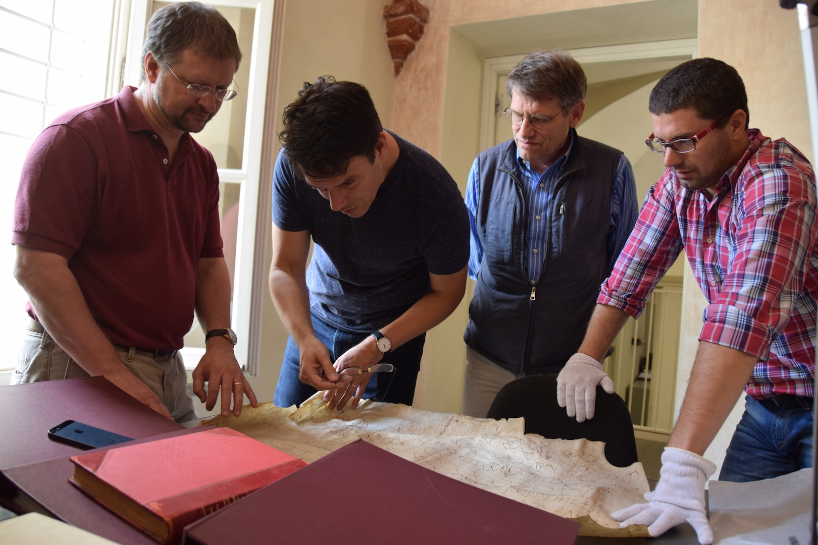 TEAMWORK: Heyworth (second from left) and colleagues Michael Phelps (left) and Roger Easton examine materials at the Archive and Capitulary Library of Vercelli, Italy, as head curator Timoty Leonardi (right) looks on. (University photo / The Lazarus Project)
